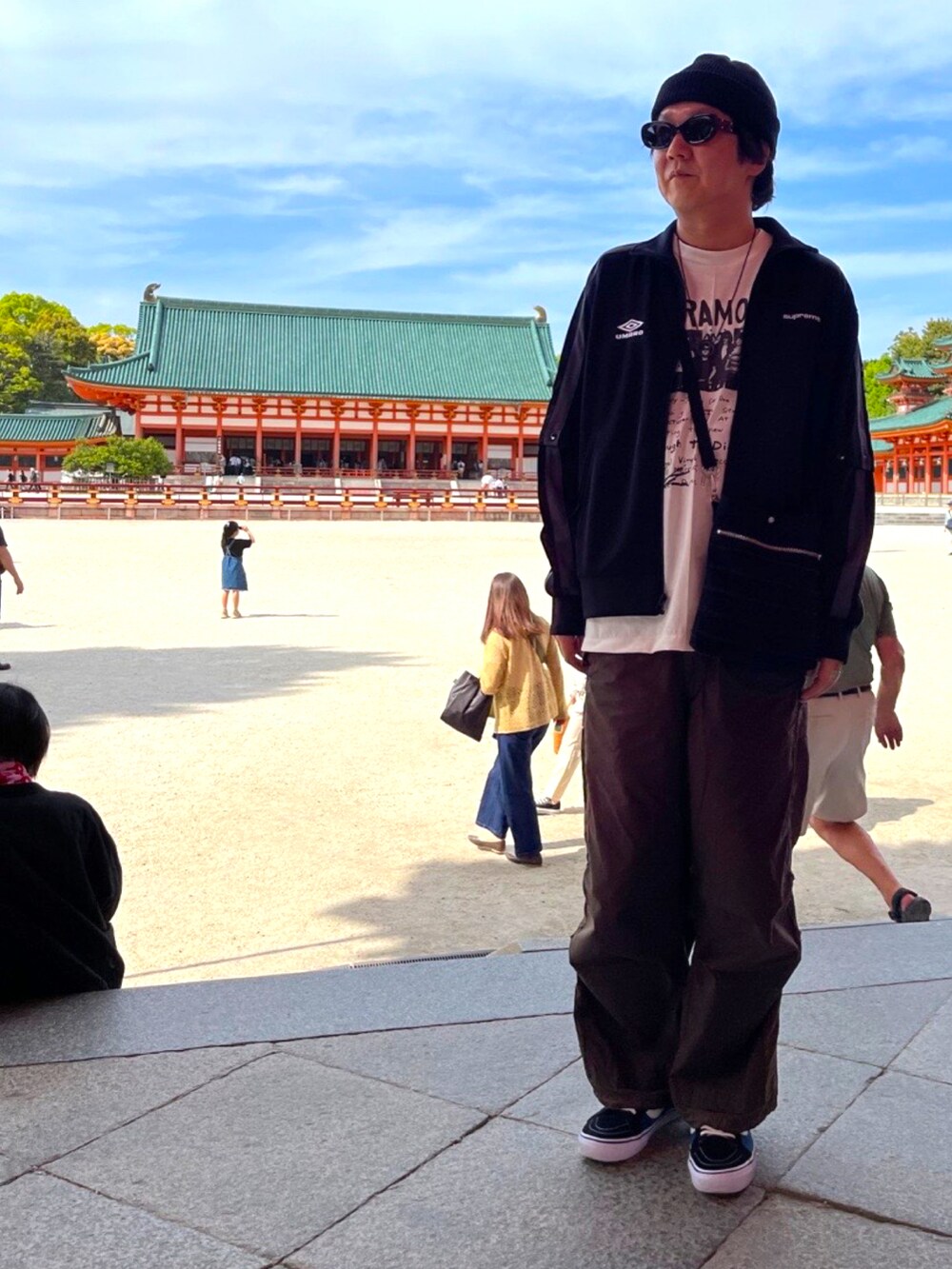 ブルー系のスニーカー、グリーン系のカーゴパンツ、ブラック系のショルダーバッグを着用したメンズの春コーディネートの2枚目の写真