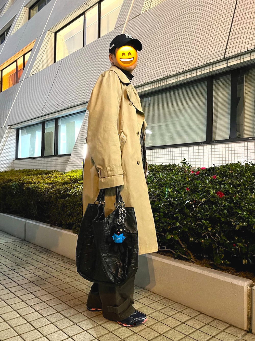 ベージュ系のトレンチコート、グレー系のカーディガン/ボレロ、ブラック系のトートバッグを着用したメンズの春コーディネートの2枚目の写真