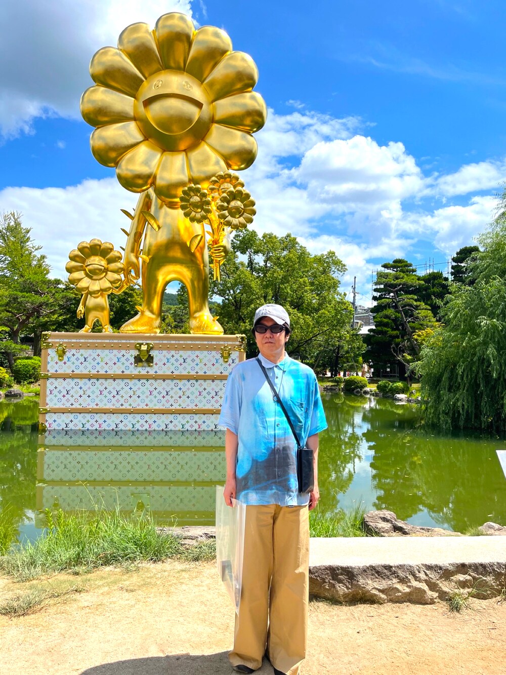 ブラック系のスニーカー、ベージュ系のチノパンツ、ブルー系のシャツ/ブラウスを着用したメンズの夏コーディネートの2枚目の写真