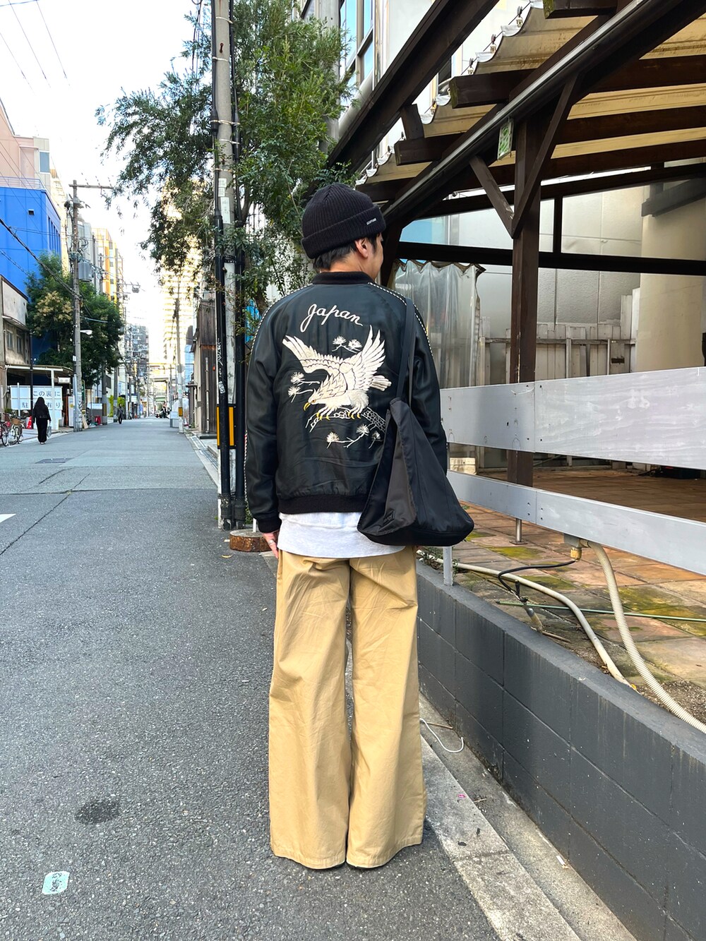 ブラック系のスニーカー、ベージュ系のチノパンツ、ブラック系のスカジャンを着用したメンズの秋コーディネートの2枚目の写真