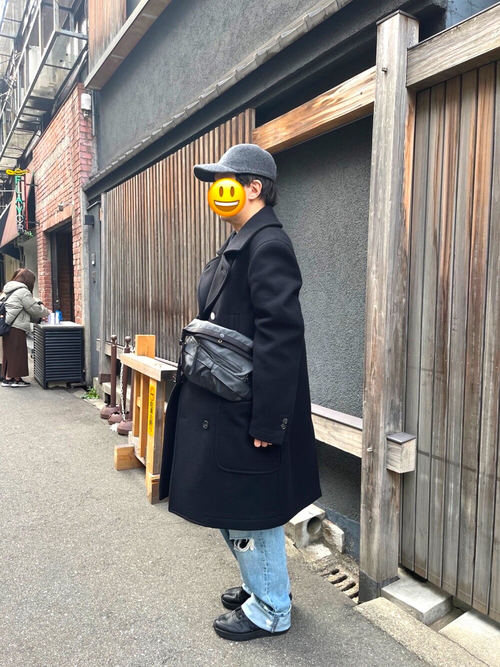 ブラック系のスニーカー、ブルー系のデニムパンツ、ブラック系のチェスターコートを着用したメンズの冬コーディネートの2枚目の写真