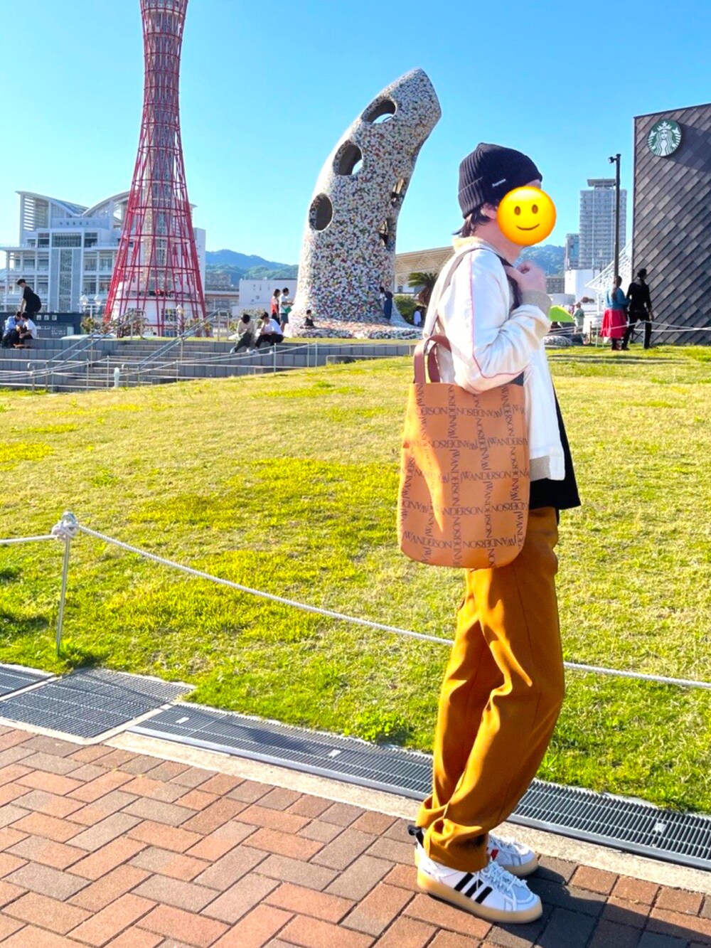 ホワイト系のスニーカー、ブラウン系のスラックス、ブラウン系のトートバッグを着用したメンズの春コーディネートの2枚目の写真