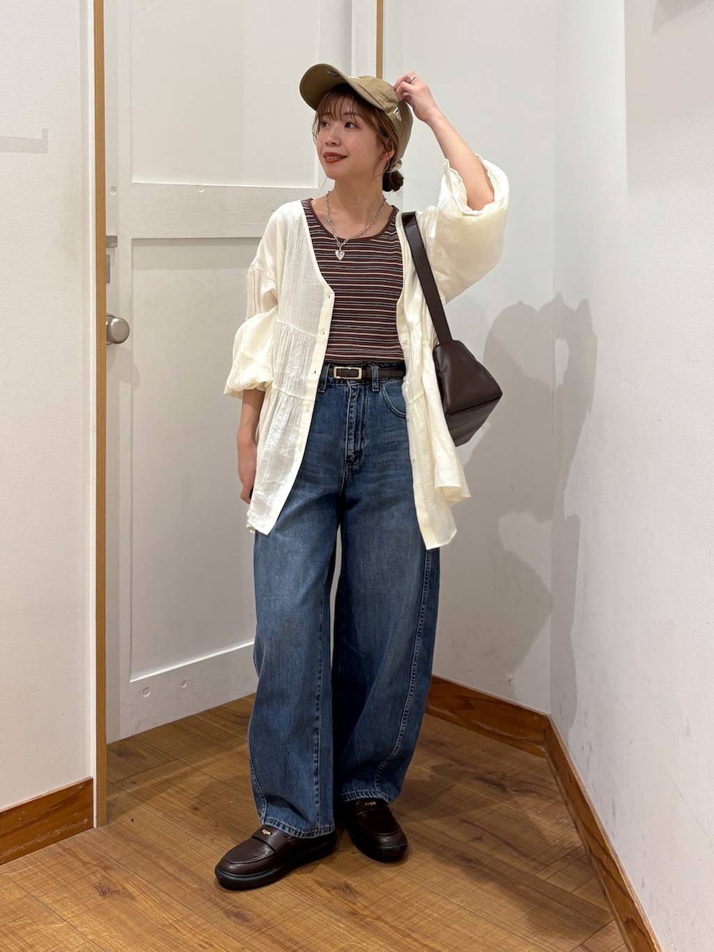 ブルー系のデニムパンツ、ブラウン系のショルダーバッグ、ブラウン系のタンクトップを着用したレディースの春コーディネートの2枚目の写真