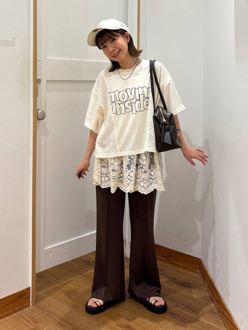 ブラウン系のボストンバッグ、ブラウン系のサンダル、ベージュ系のTシャツ/カットソーを着用したレディースの夏コーディネートの6枚目の写真