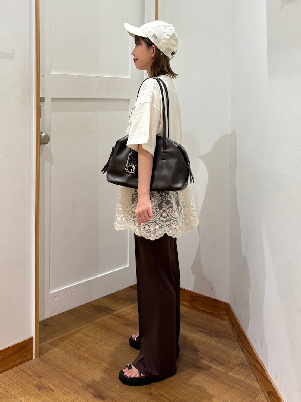 ブラウン系のボストンバッグ、ブラウン系のサンダル、ベージュ系のTシャツ/カットソーを着用したレディースの夏コーディネートの2枚目の写真