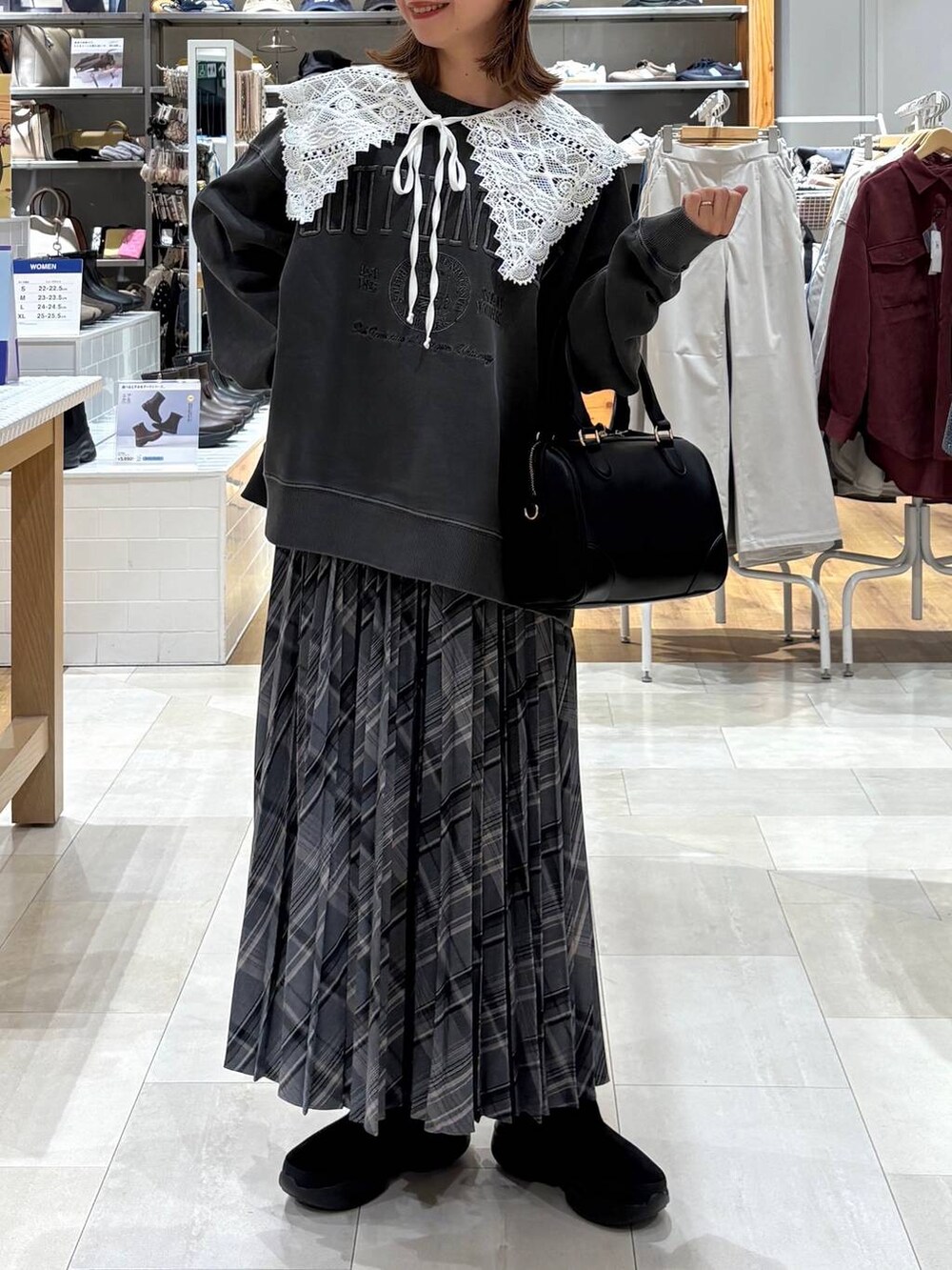 ブラック系のブーツ、グレー系のスカート、ブラック系のボストンバッグを着用したレディースの秋コーディネートの5枚目の写真