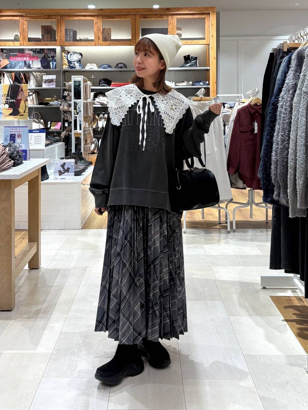 ブラック系のブーツ、グレー系のスカート、ブラック系のボストンバッグを着用したレディースの秋コーディネートの8枚目の写真