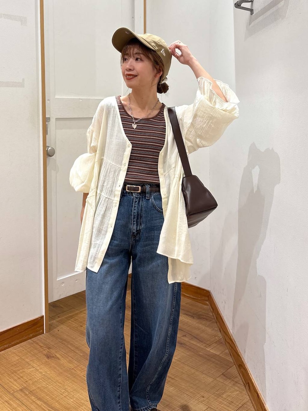 ブルー系のデニムパンツ、ブラウン系のショルダーバッグ、ブラウン系のタンクトップを着用したレディースの春コーディネートの5枚目の写真