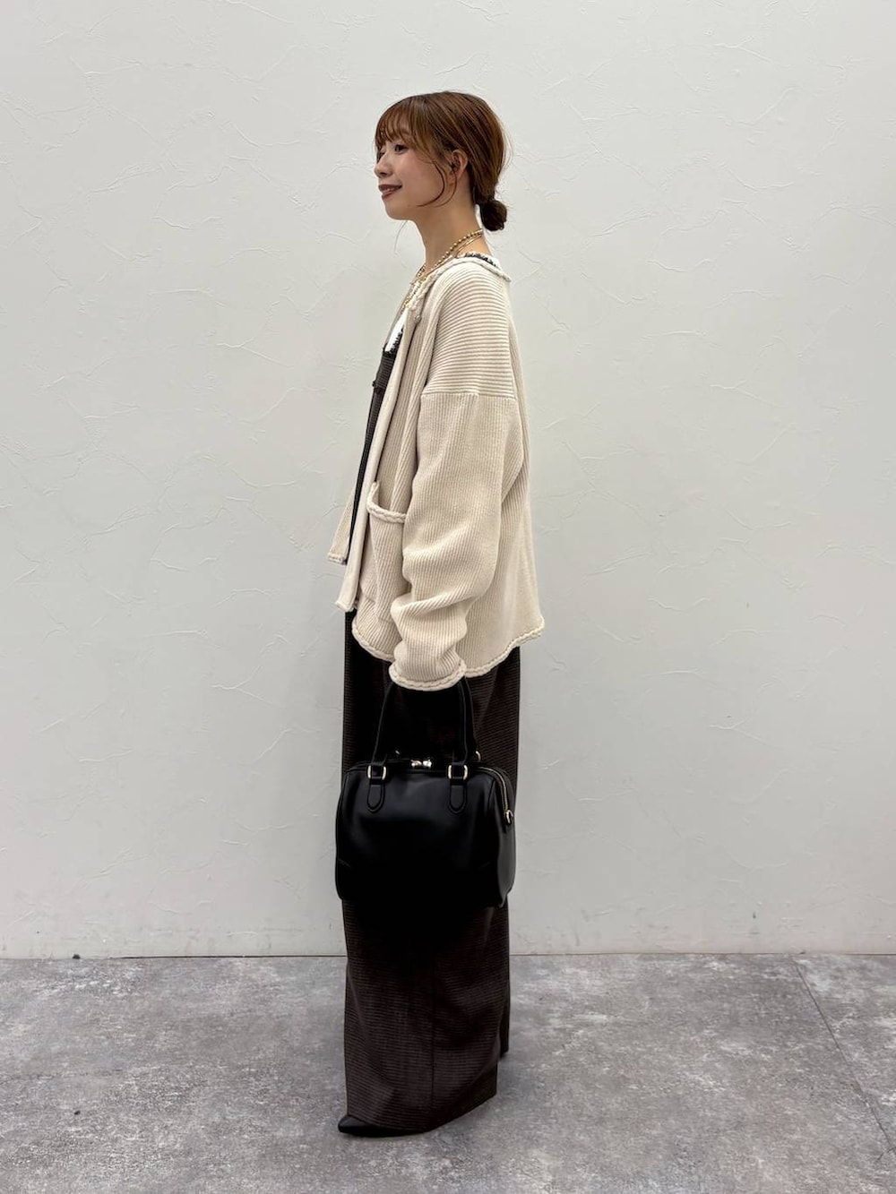 ベージュ系のTシャツ/カットソー、ベージュ系のカーディガン/ボレロ、ブラック系のボストンバッグを着用したレディースの冬コーディネートの2枚目の写真