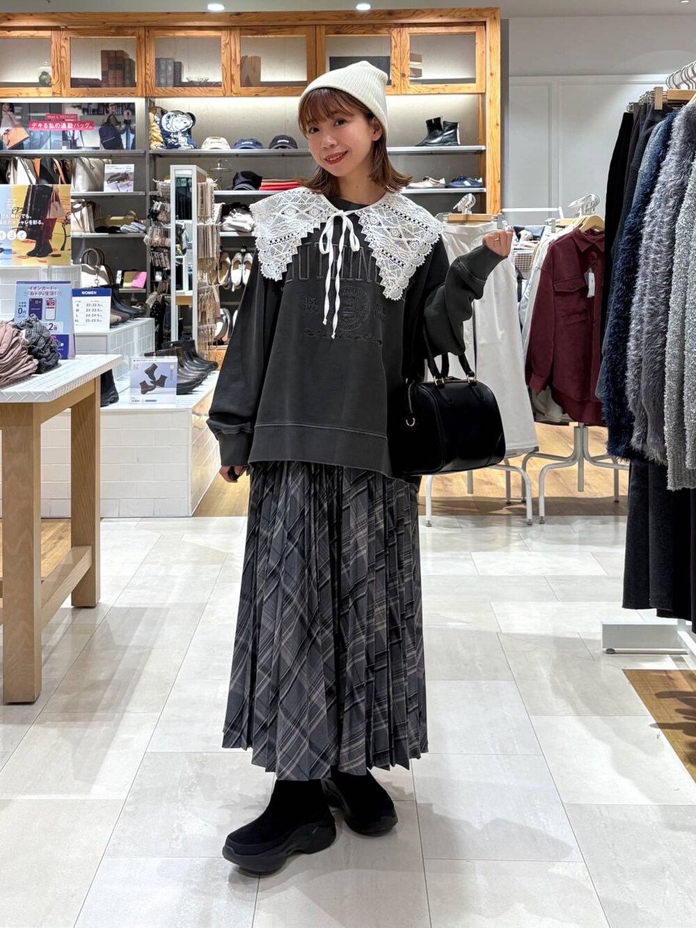 ブラック系のブーツ、グレー系のスカート、ブラック系のボストンバッグを着用したレディースの秋コーディネートの4枚目の写真