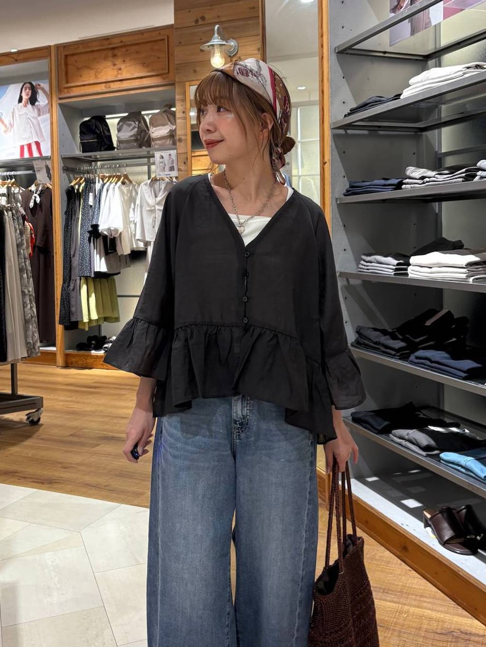 ブルー系のデニムパンツ、ホワイト系のタンクトップ、ブラウン系のクラッチバッグを着用したレディースの夏コーディネートの5枚目の写真