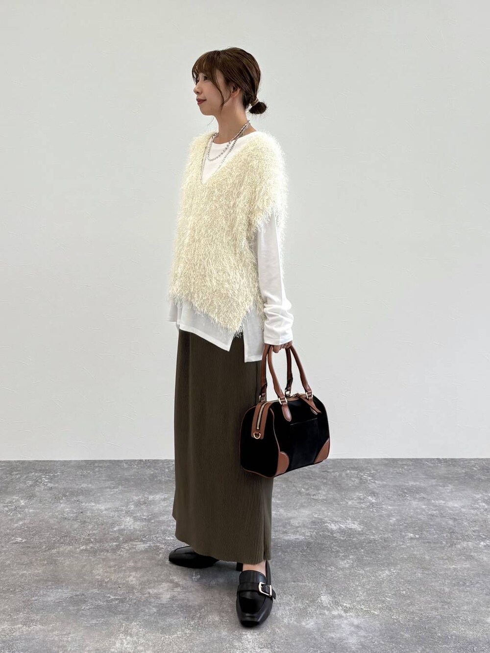 ブラック系のローファー、ベージュ系のタンクトップ、グリーン系のスカートを着用したレディースの夏コーディネートの2枚目の写真