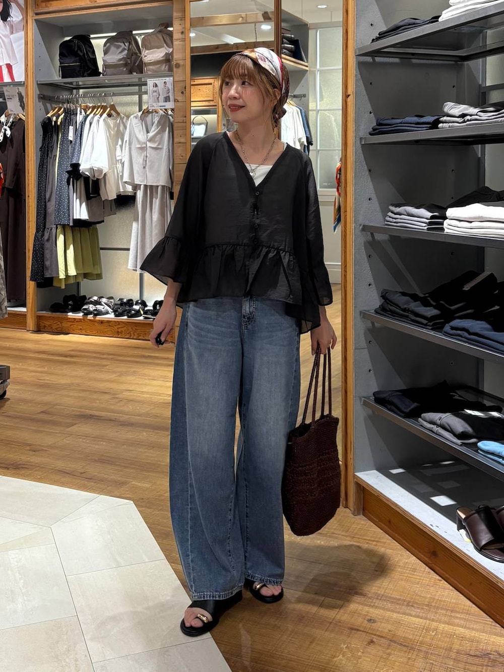 ブルー系のデニムパンツ、ホワイト系のタンクトップ、ブラウン系のクラッチバッグを着用したレディースの夏コーディネートの6枚目の写真