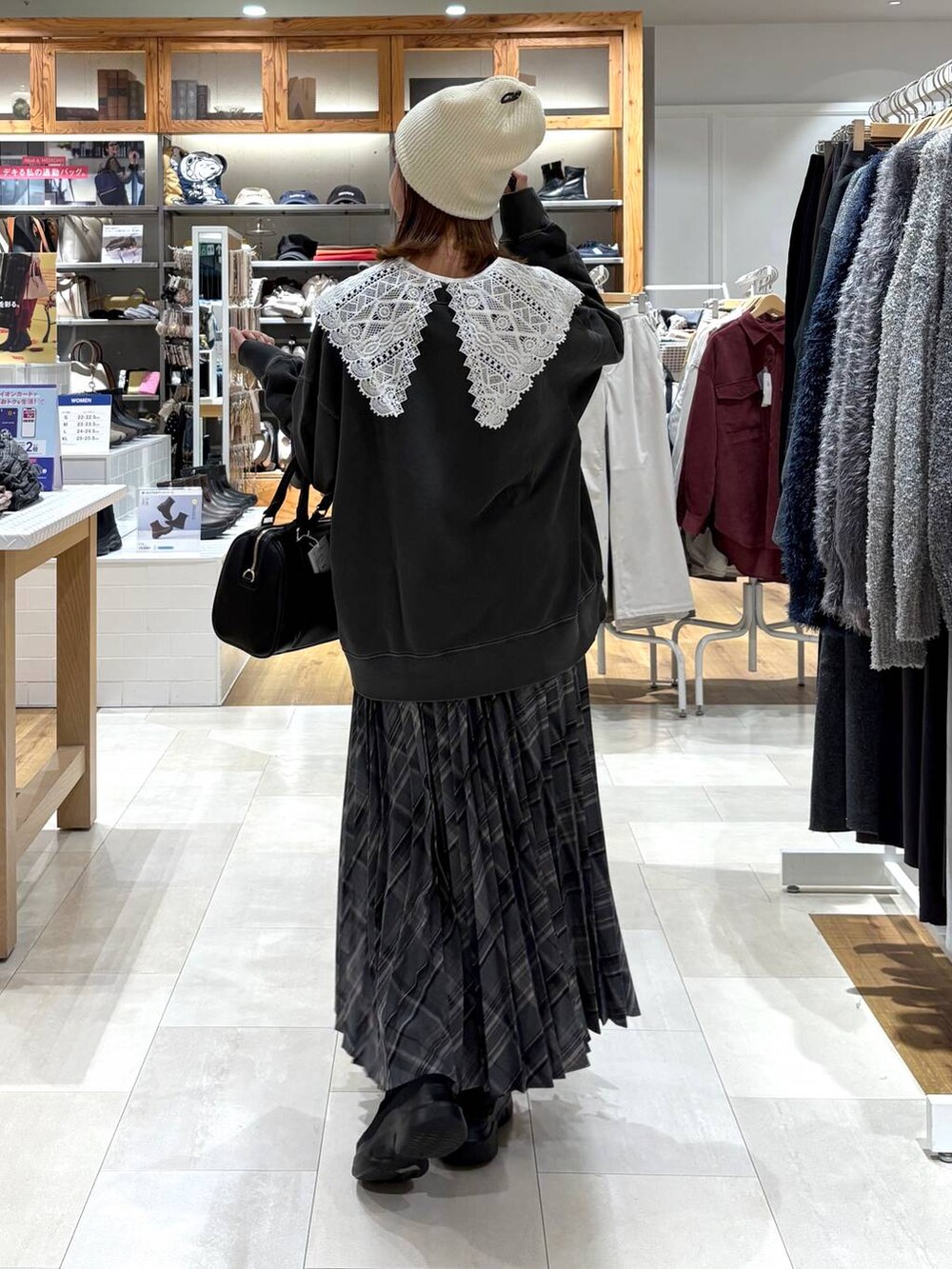 ブラック系のブーツ、グレー系のスカート、ブラック系のボストンバッグを着用したレディースの秋コーディネートの3枚目の写真