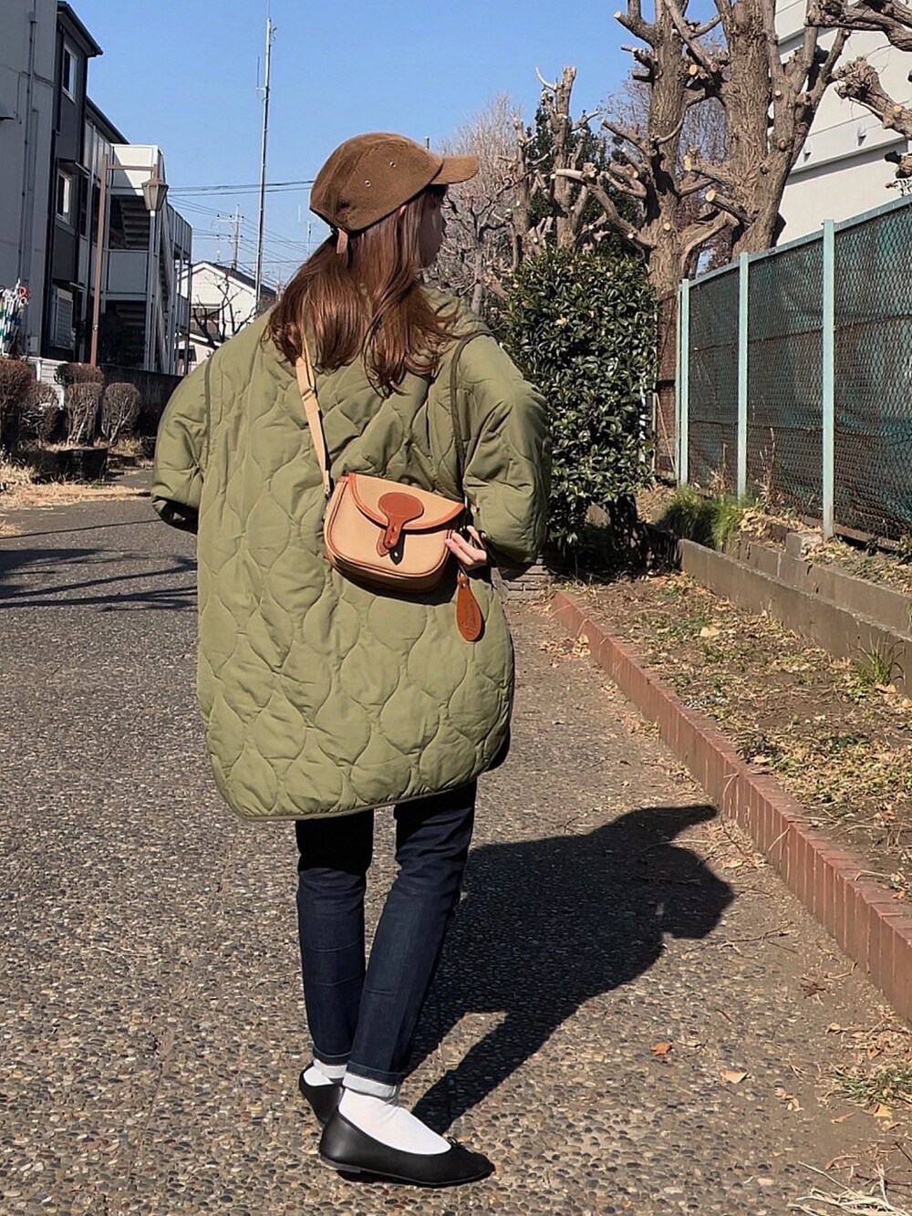 グリーン系のノーカラージャケット、ベージュ系のショルダーバッグ、ブラック系のデニムパンツを着用したレディースの冬コーディネートの2枚目の写真