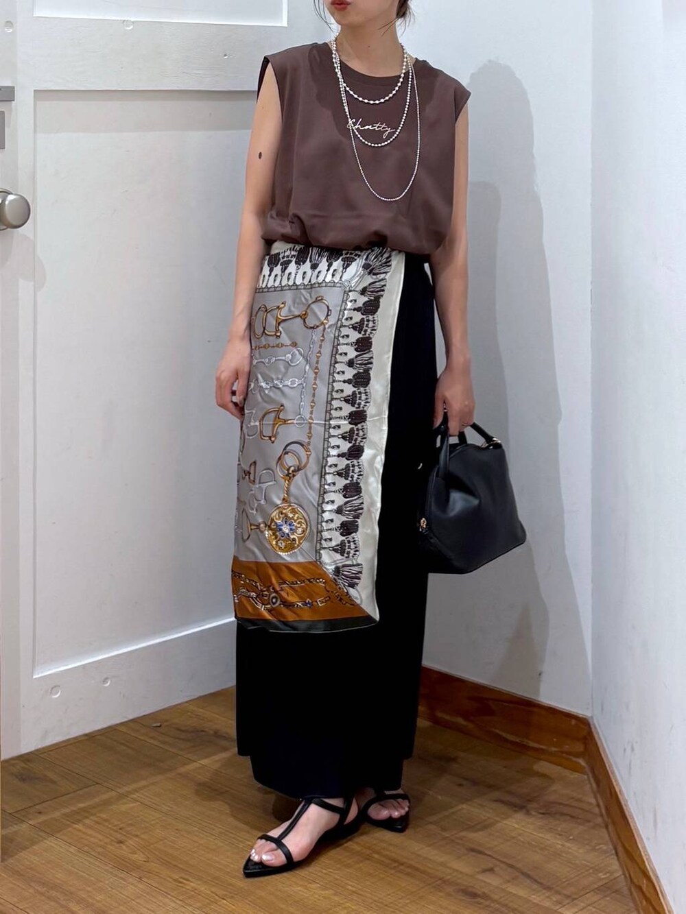 ブラック系のショルダーバッグ、ブラック系のスカート、ブラック系のサンダルを着用したレディースの夏コーディネートの4枚目の写真