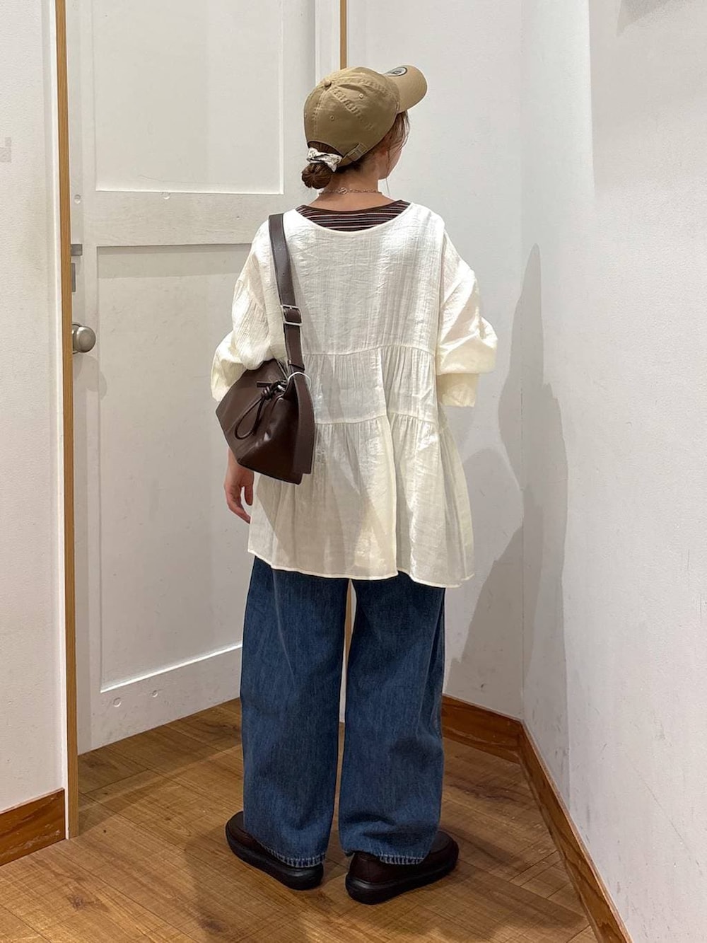 ブルー系のデニムパンツ、ブラウン系のショルダーバッグ、ブラウン系のタンクトップを着用したレディースの春コーディネートの4枚目の写真