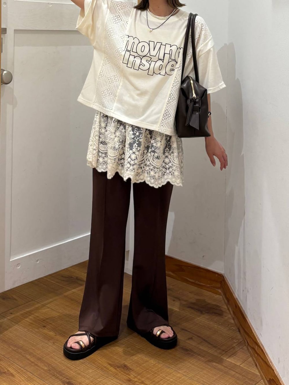 ブラウン系のボストンバッグ、ブラウン系のサンダル、ベージュ系のTシャツ/カットソーを着用したレディースの夏コーディネートの4枚目の写真