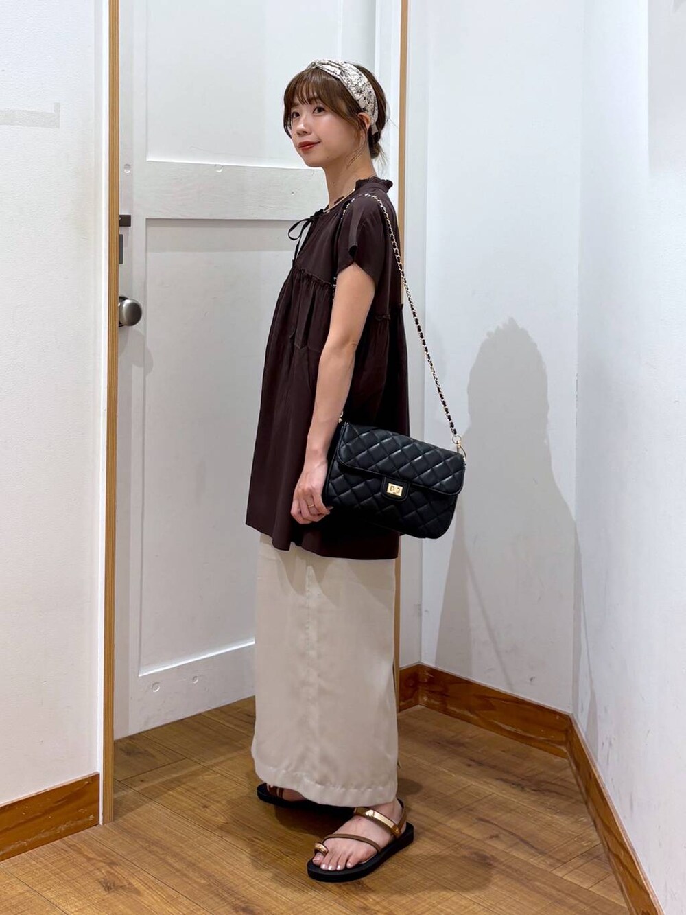 ブラック系のショルダーバッグ、ブラック系のタンクトップ、グレー系のスカートを着用したレディースの夏コーディネートの2枚目の写真