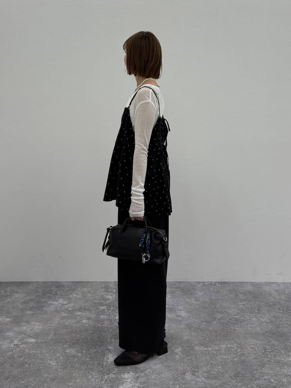 ブラック系のボストンバッグ、ブルー系のベスト、ブラック系のパンプスを着用したレディースの春コーディネートの2枚目の写真