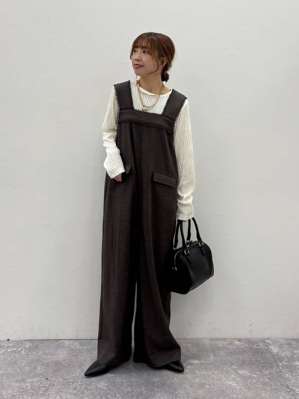 ベージュ系のTシャツ/カットソー、ベージュ系のカーディガン/ボレロ、ブラック系のボストンバッグを着用したレディースの冬コーディネートの4枚目の写真