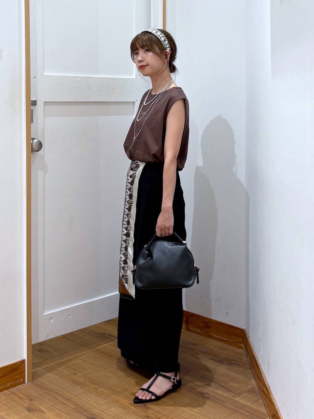 ブラック系のショルダーバッグ、ブラック系のスカート、ブラック系のサンダルを着用したレディースの夏コーディネートの2枚目の写真