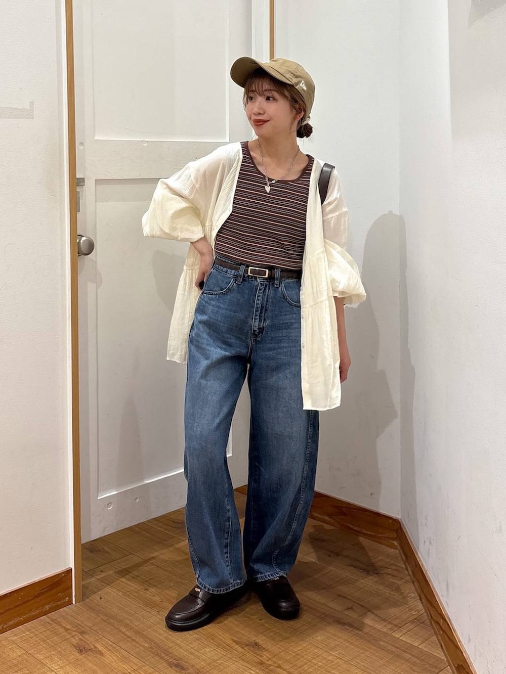 ブルー系のデニムパンツ、ブラウン系のショルダーバッグ、ブラウン系のタンクトップを着用したレディースの春コーディネートの7枚目の写真