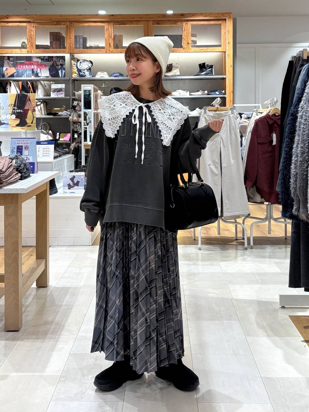 ブラック系のブーツ、グレー系のスカート、ブラック系のボストンバッグを着用したレディースの秋コーディネートの6枚目の写真