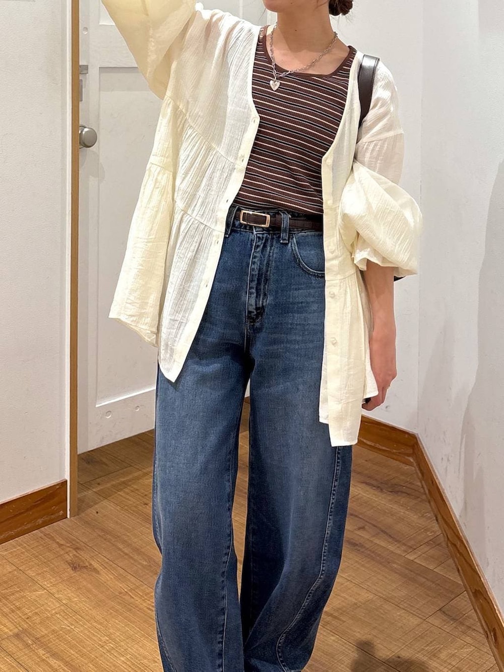 ブルー系のデニムパンツ、ブラウン系のショルダーバッグ、ブラウン系のタンクトップを着用したレディースの春コーディネートの6枚目の写真