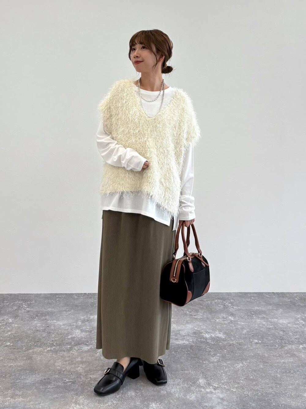 ブラック系のローファー、ベージュ系のタンクトップ、グリーン系のスカートを着用したレディースの夏コーディネートの5枚目の写真