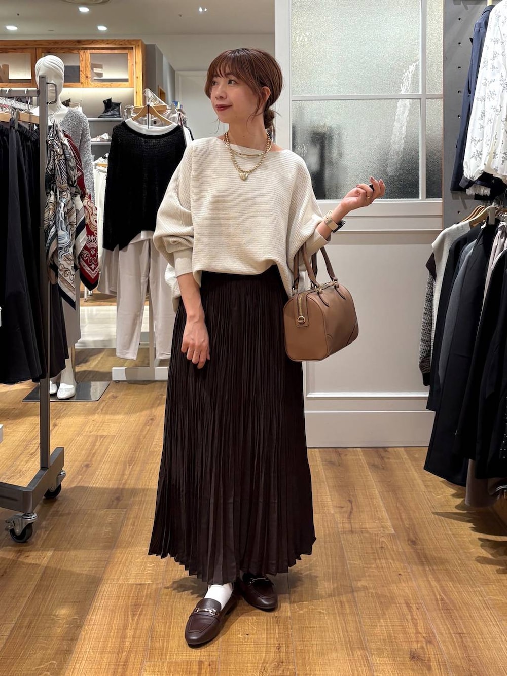 ブラウン系のローファー、グレー系のニット/セーター、ベージュ系のボストンバッグを着用したレディースの秋コーディネートの5枚目の写真