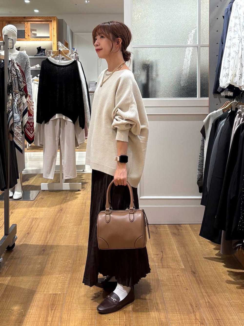ブラウン系のローファー、グレー系のニット/セーター、ベージュ系のボストンバッグを着用したレディースの秋コーディネートの2枚目の写真