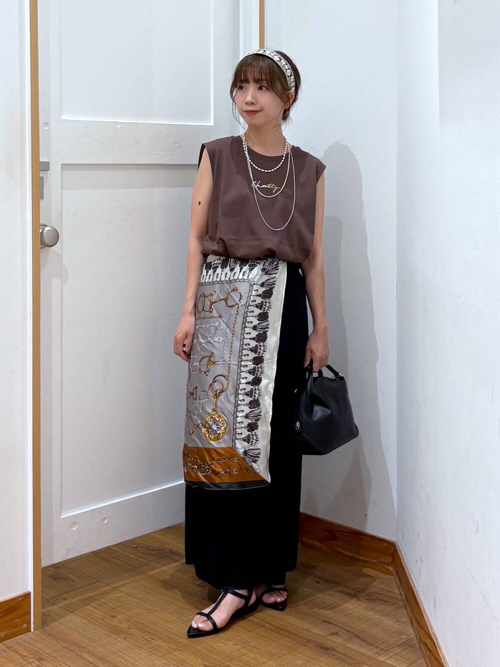 ブラック系のショルダーバッグ、ブラック系のスカート、ブラック系のサンダルを着用したレディースの夏コーディネートの5枚目の写真