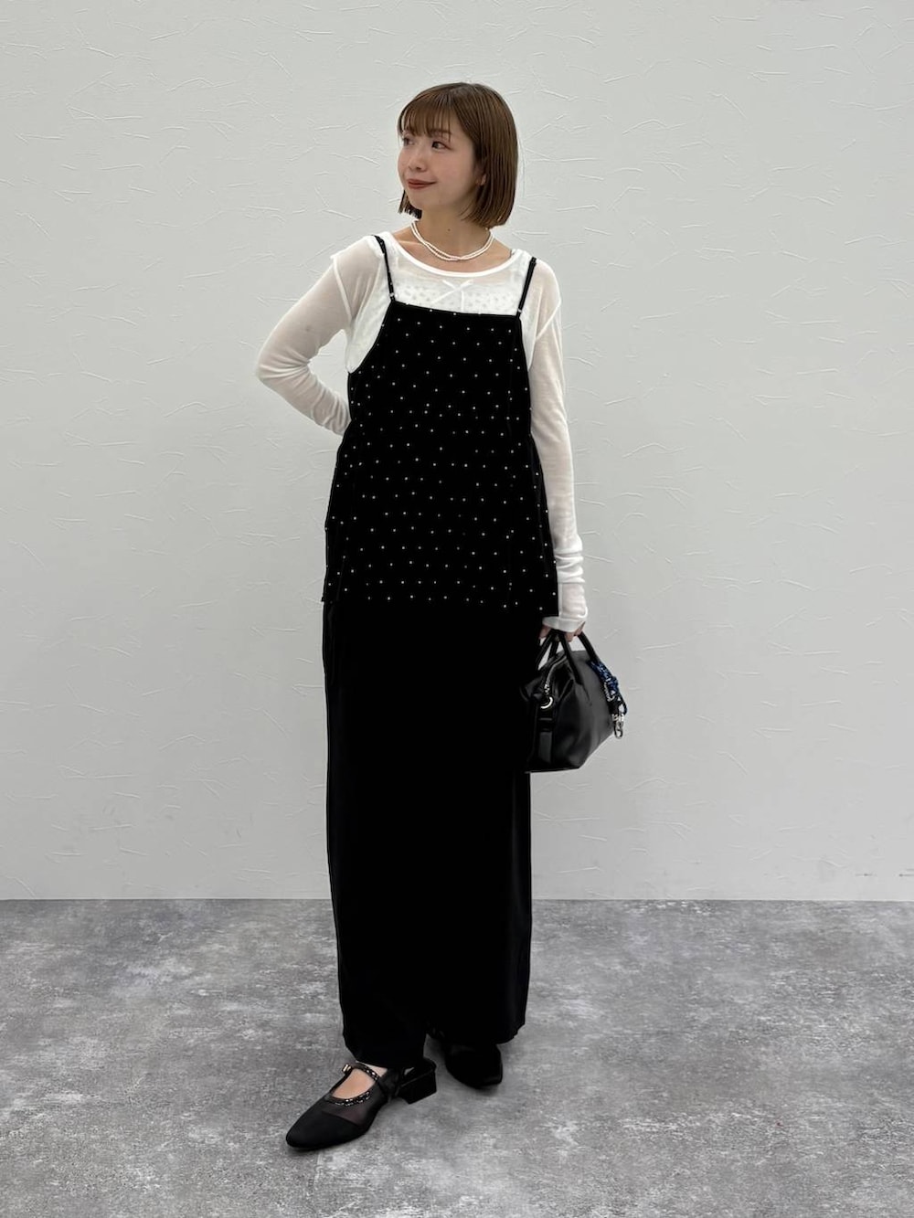 ブラック系のボストンバッグ、ブルー系のベスト、ブラック系のパンプスを着用したレディースの春コーディネートの6枚目の写真