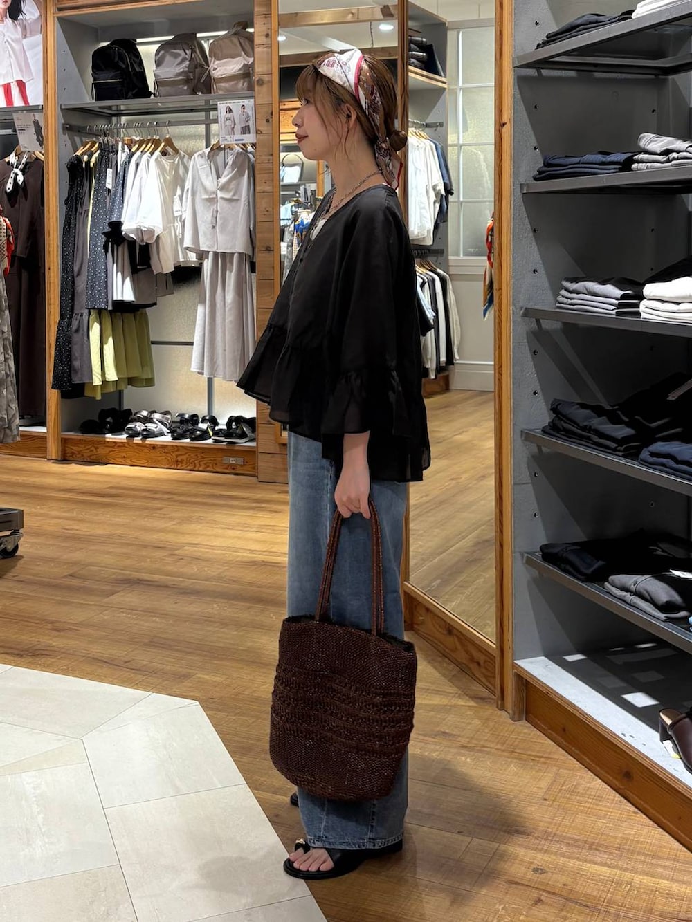 ブルー系のデニムパンツ、ホワイト系のタンクトップ、ブラウン系のクラッチバッグを着用したレディースの夏コーディネートの2枚目の写真