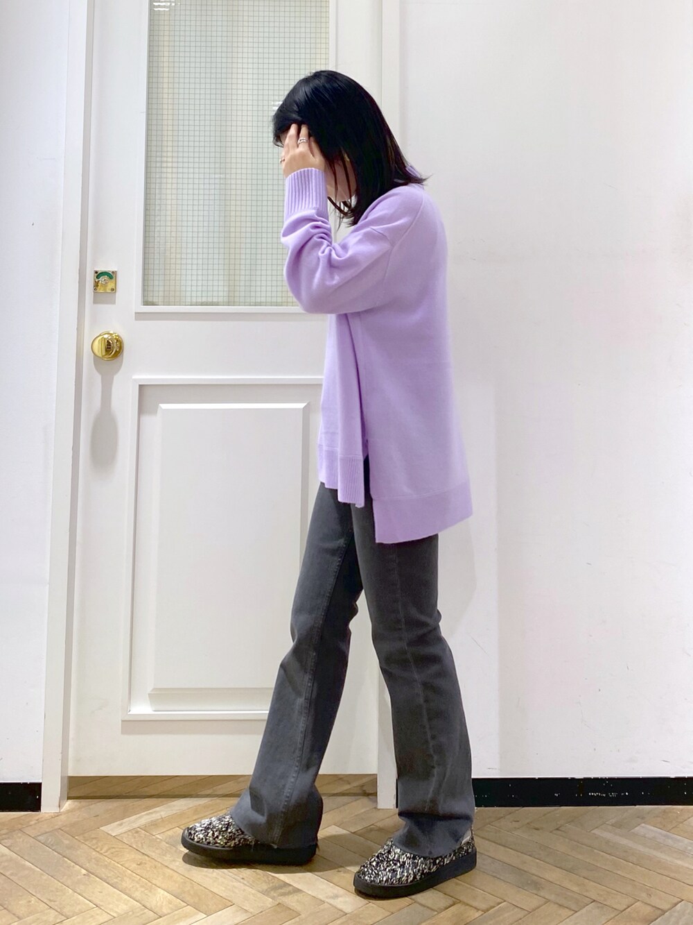 パープル系のニット/セーター、ブラック系のデニムパンツ、ブラック系のスリッポンを着用したレディースの冬コーディネートの2枚目の写真