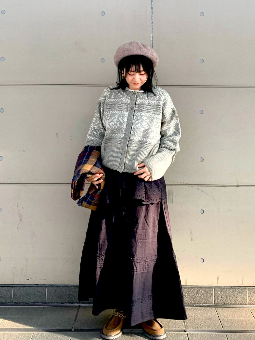 グレー系のニット/セーター、ブラック系のスカート、ベージュ系のTシャツ/カットソーを着用したレディースの秋コーディネートの3枚目の写真