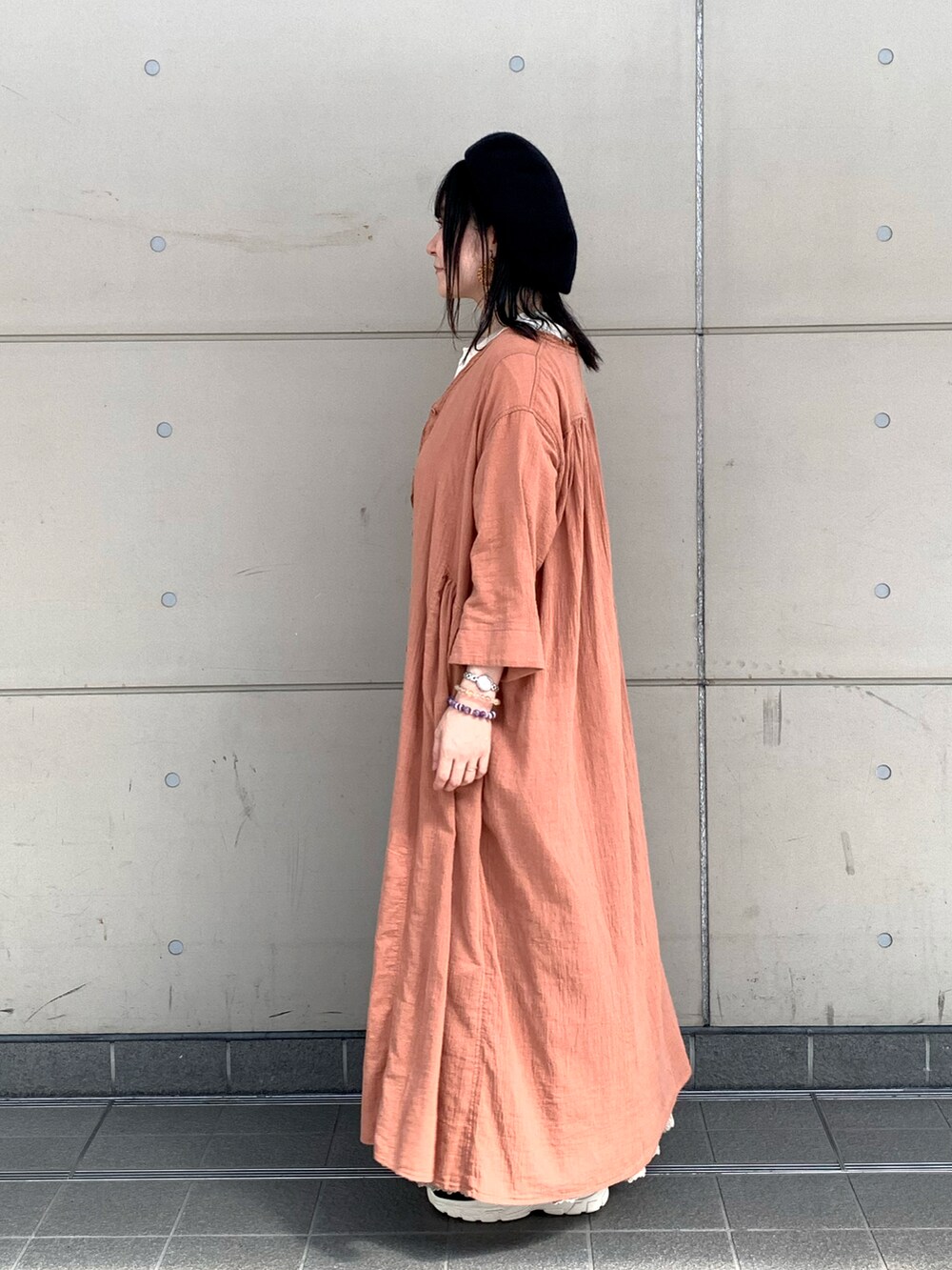 ベージュ系のTシャツ/カットソー、オレンジ系のワンピース/ドレス、ベージュ系のスカートを着用したレディースの夏コーディネートの2枚目の写真