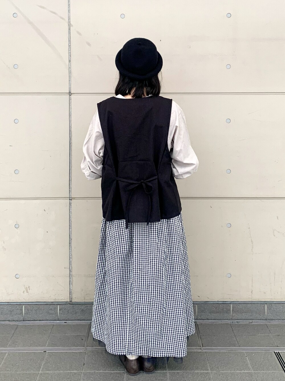 ベージュ系のシャツ/ブラウス、ブラック系のベスト、ブルー系のスカートを着用したレディースの秋コーディネートの2枚目の写真