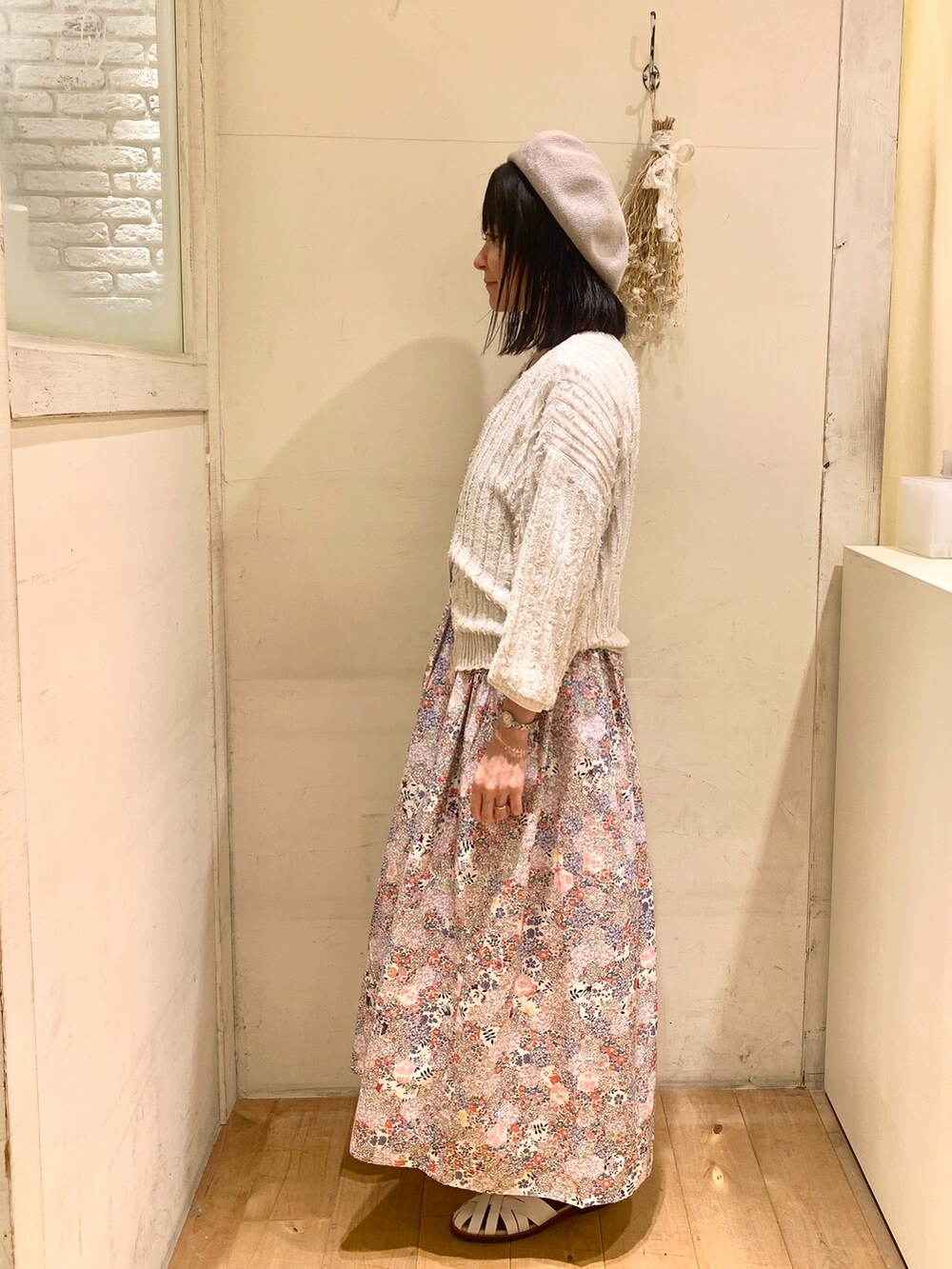 ベージュ系のカーディガン/ボレロ、ピンク系のワンピース/ドレス、ホワイト系のサンダルを着用したレディースの春コーディネートの2枚目の写真