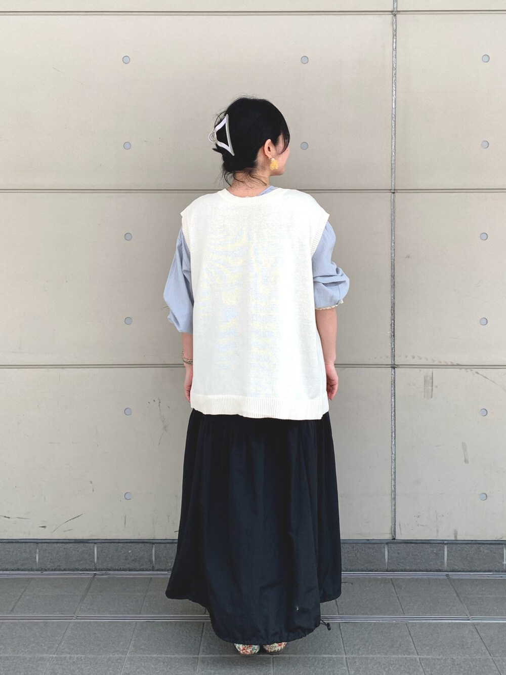ホワイト系のベスト、ブルー系のシャツ/ブラウス、ブラック系のスカートを着用したレディースの春コーディネートの3枚目の写真
