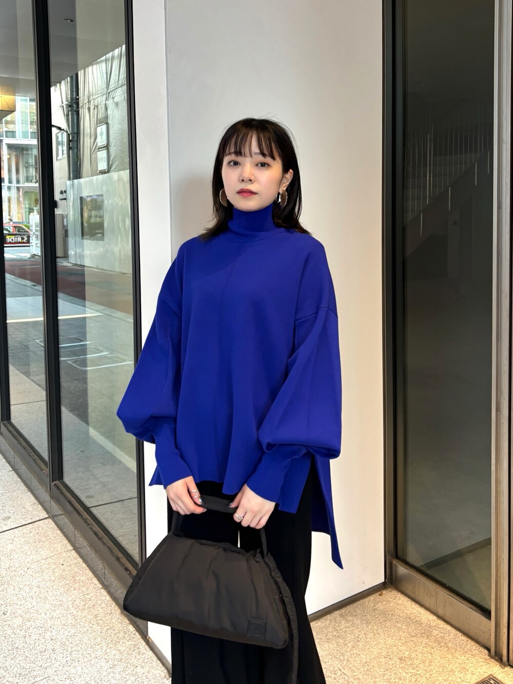 ブラック系のハンドバッグ、ブルー系のニット/セーター、ブラック系のその他パンツを着用したレディースの秋コーディネートの4枚目の写真