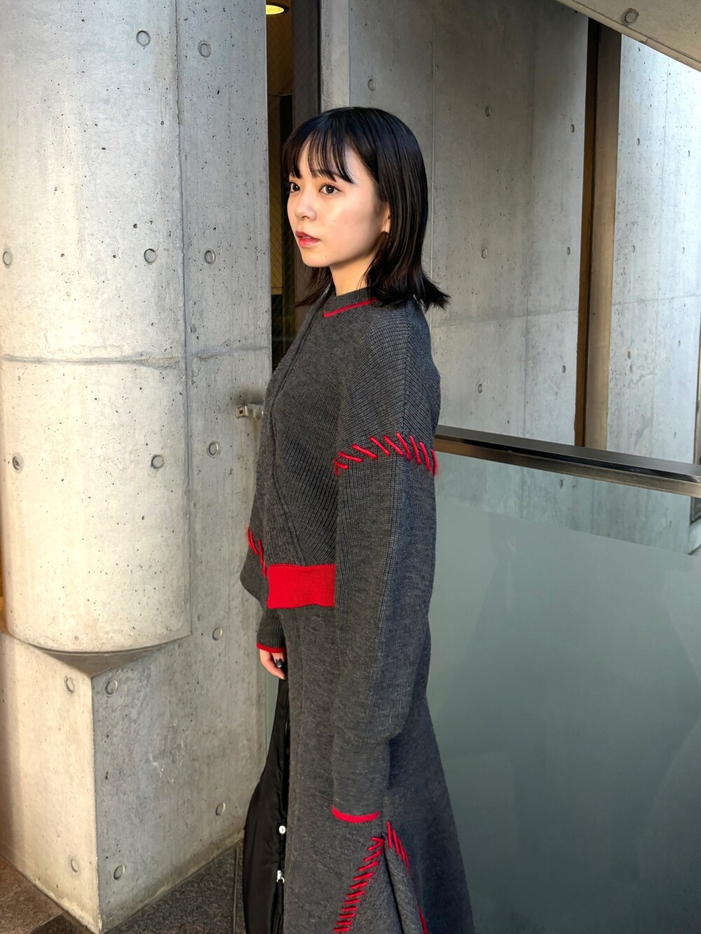 グレー系のニット/セーター、グレー系のスカート、ブラック系のハンドバッグを着用したレディースの秋コーディネートの4枚目の写真