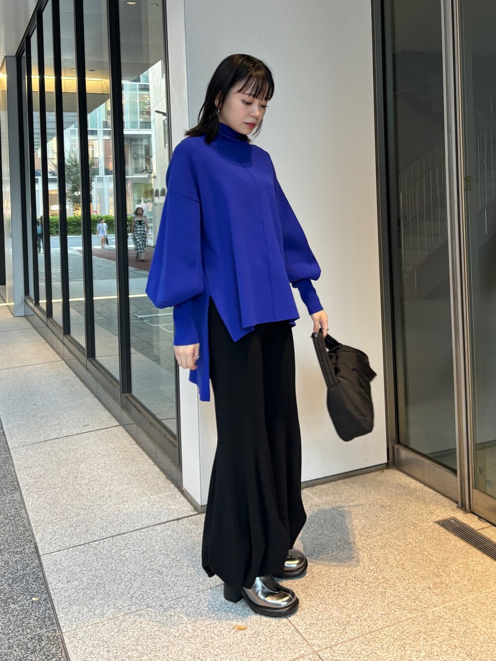 ブラック系のハンドバッグ、ブルー系のニット/セーター、ブラック系のその他パンツを着用したレディースの秋コーディネートの2枚目の写真