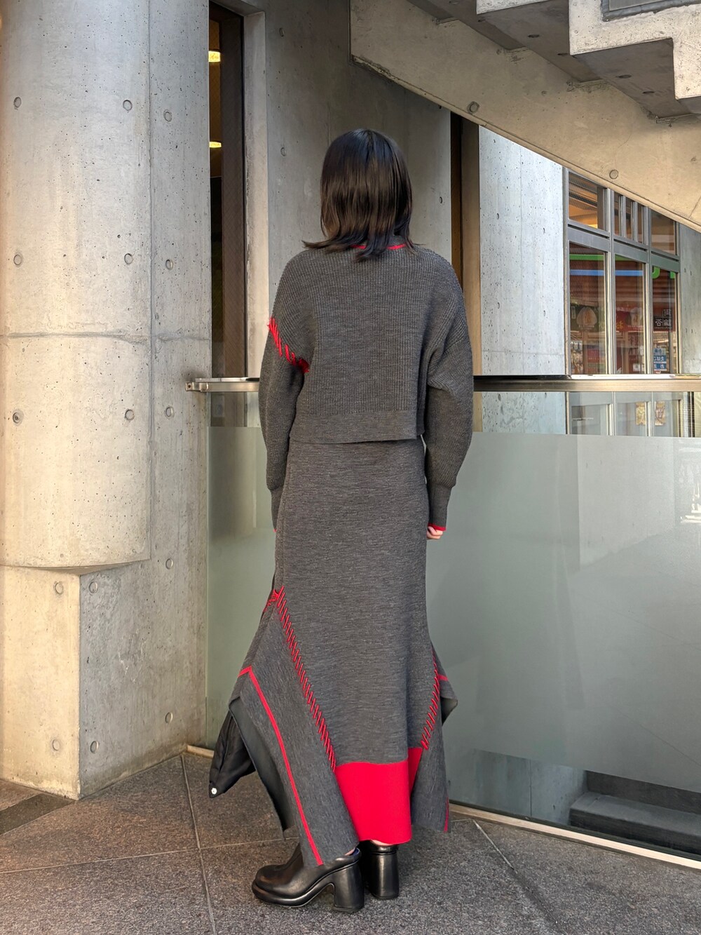 グレー系のニット/セーター、グレー系のスカート、ブラック系のハンドバッグを着用したレディースの秋コーディネートの3枚目の写真