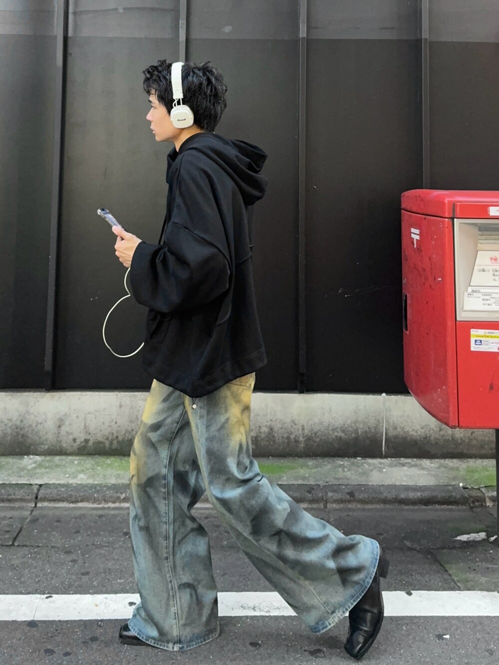 ブラック系のパーカー、ブルー系のデニムパンツを着用したメンズの秋コーディネートの3枚目の写真