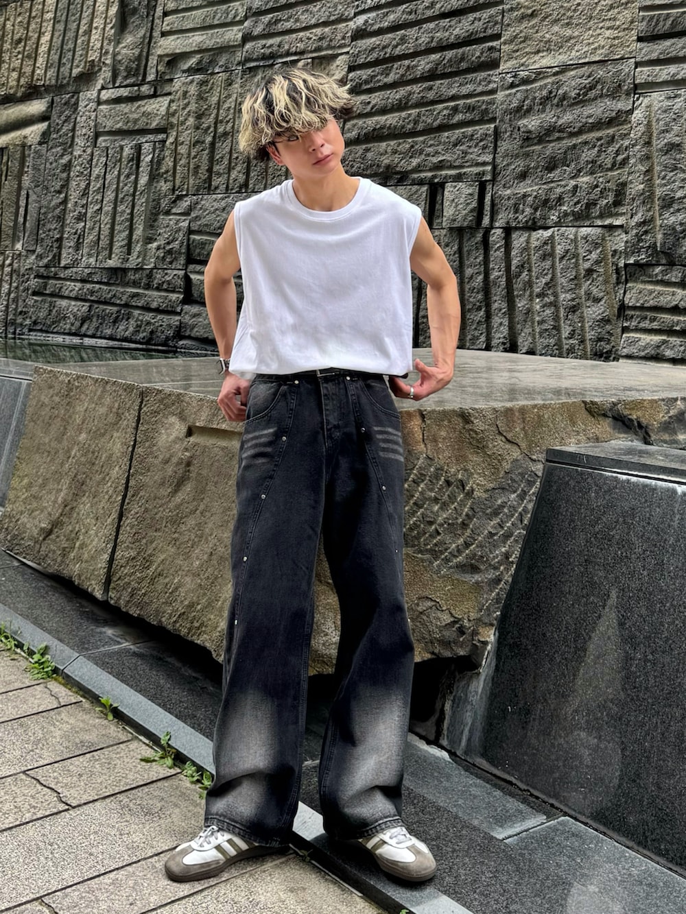 ブラック系のトップス、ブルー系のデニムパンツ、ホワイト系のスニーカーを着用したメンズの夏コーディネートの2枚目の写真