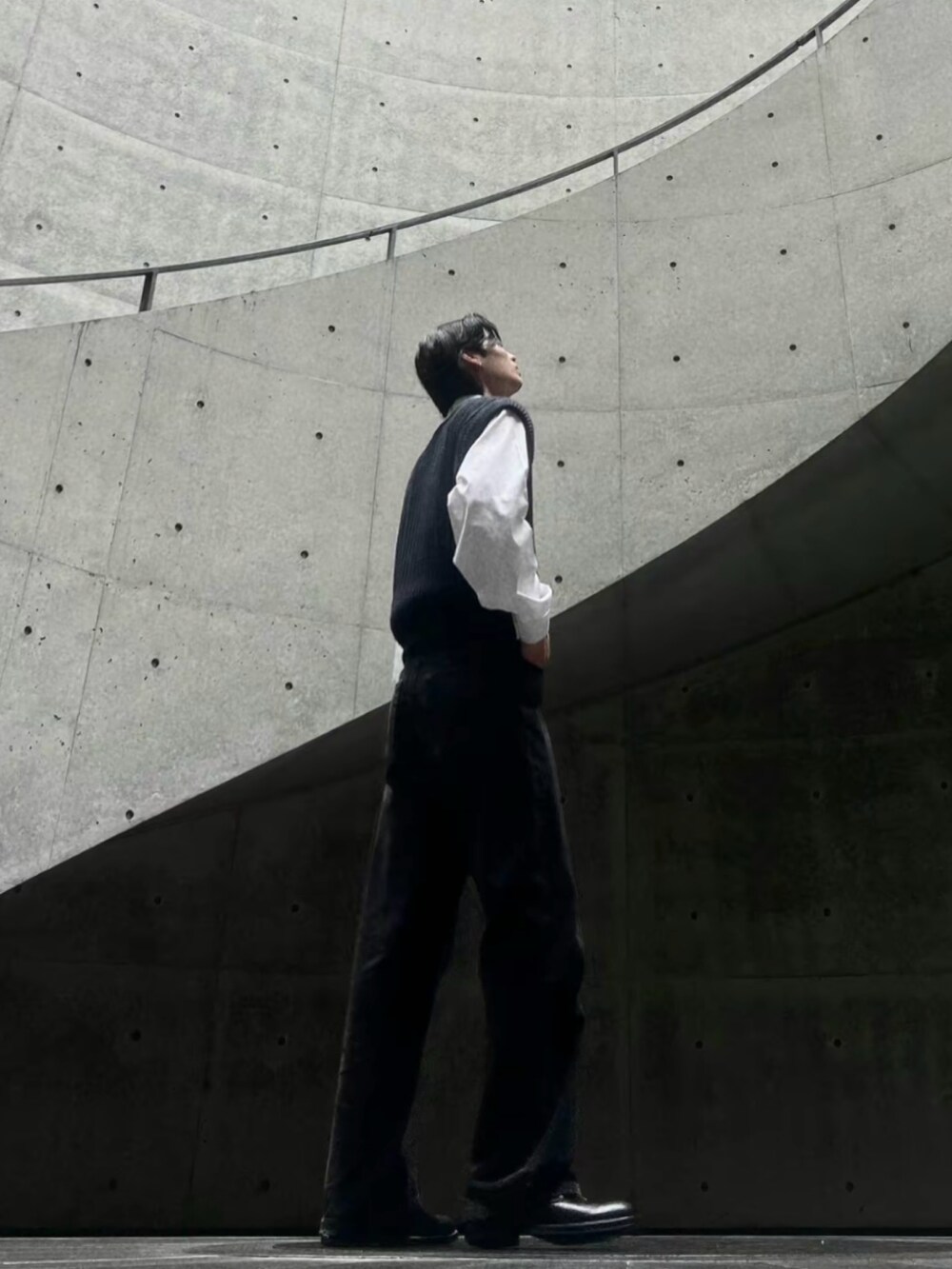 ブラック系のニット/セーター、ホワイト系のシャツ/ブラウス、グレー系のデニムパンツを着用したメンズの春コーディネートの2枚目の写真