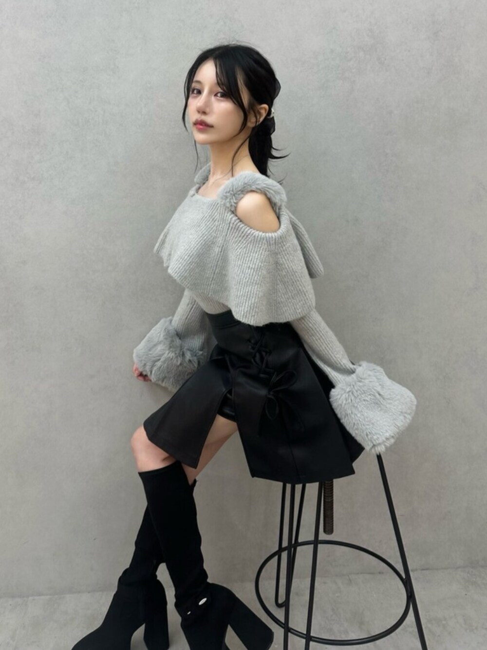 グレー系のニット/セーター、ブラック系のスカート、ブラック系のブーツを着用したレディースの秋コーディネートの7枚目の写真