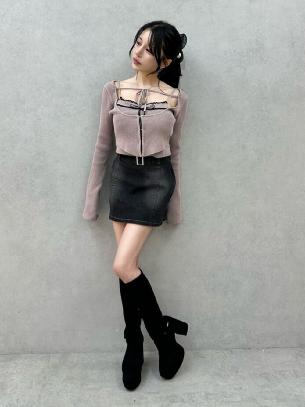 ブラック系のデニムスカート、ブラック系のブーツ、ベージュ系のニット/セーターを着用したレディースの秋コーディネートの3枚目の写真